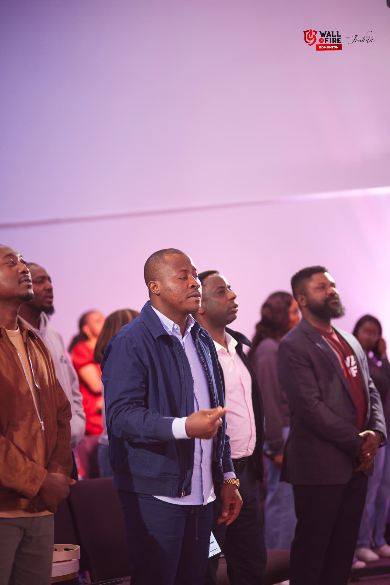 Men standing in worship in the crowd