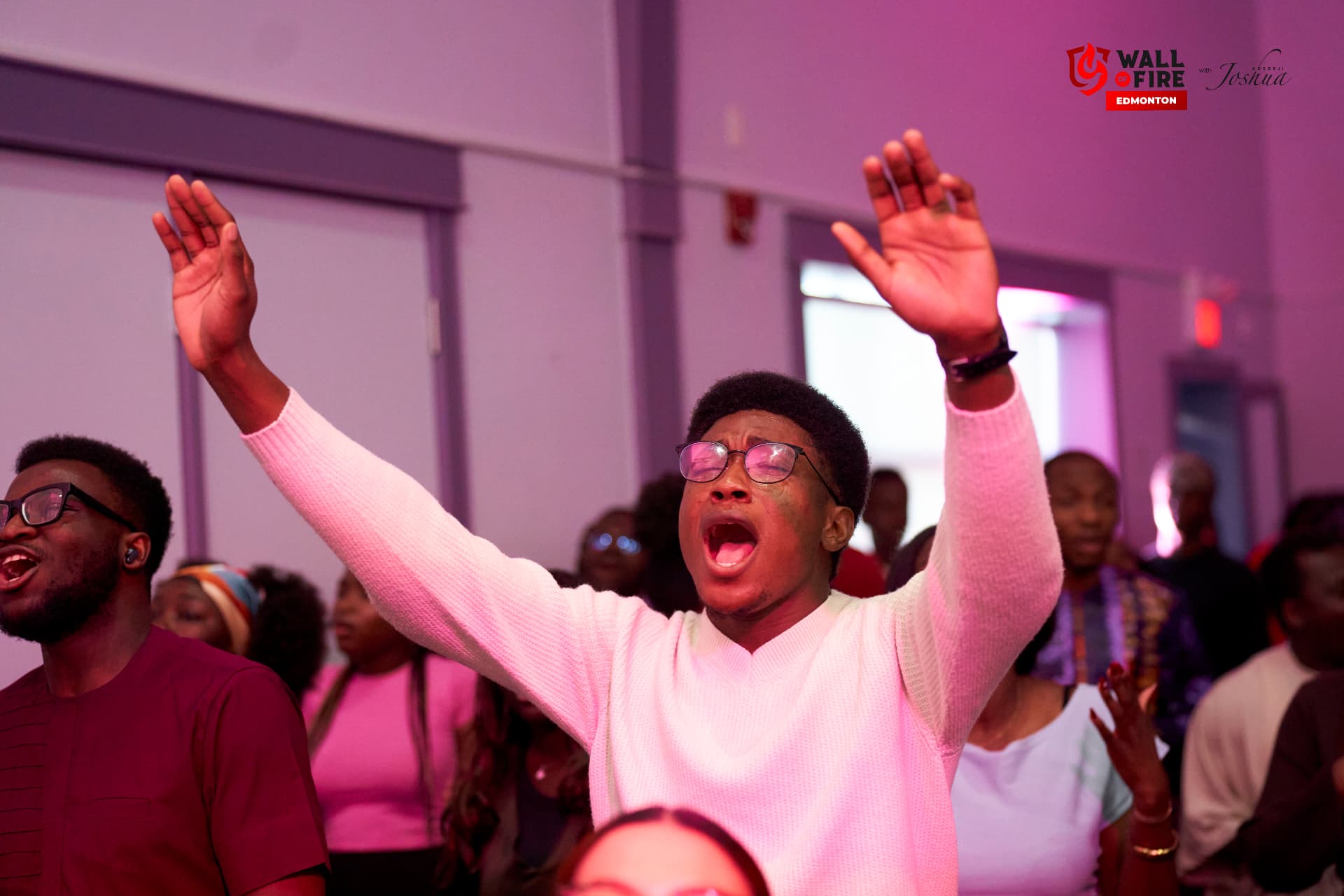 A young man with both hands raised singing